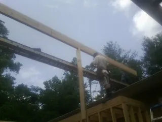 Carpenter setting a ridge beam over a new addition frame — Ice Dam Removal by Roofing Brothers in Petroleum