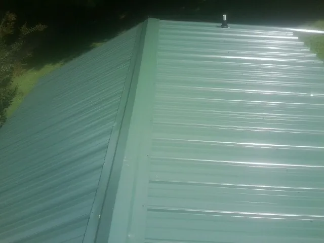 New green metal panels meeting at the ridge of a roof — Flat Roof Repair work by our crew in Petroleum