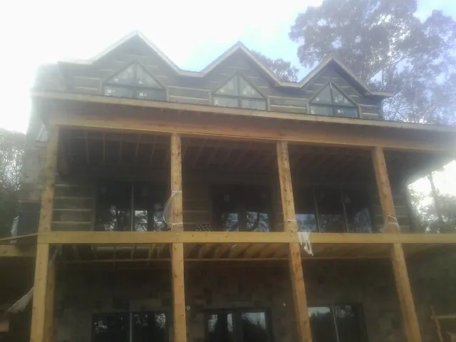 Dormers and porch framing on a large log home under construction — Roof Coating work by our crew in Petroleum