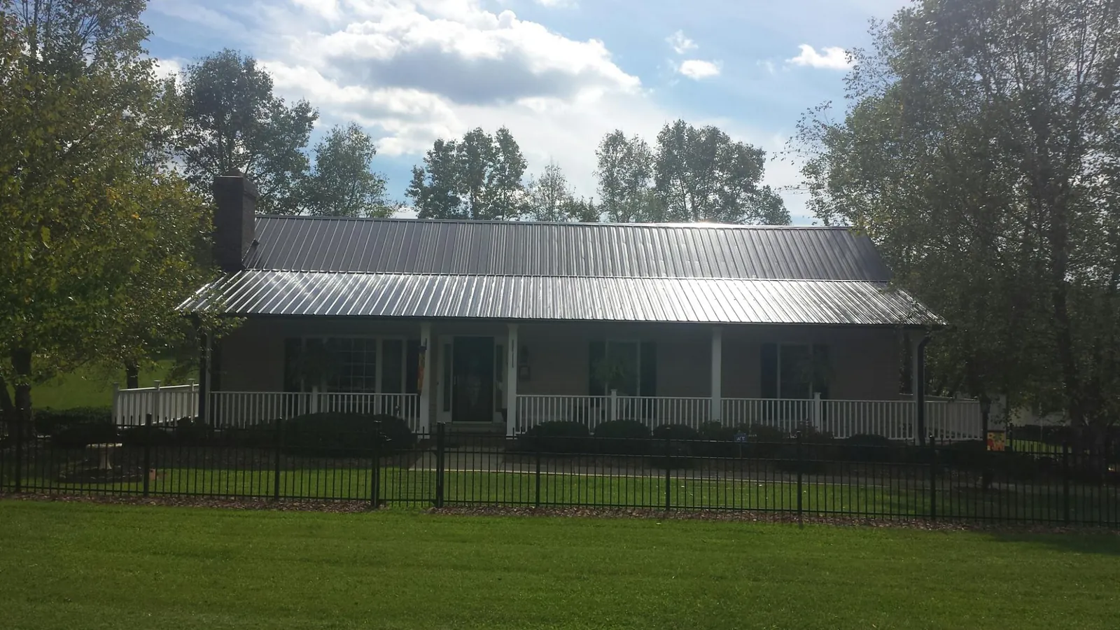 Gray metal roof on a brick ranch with a full width front porch — Gutter Guard Installation work by our crew in Petroleum
