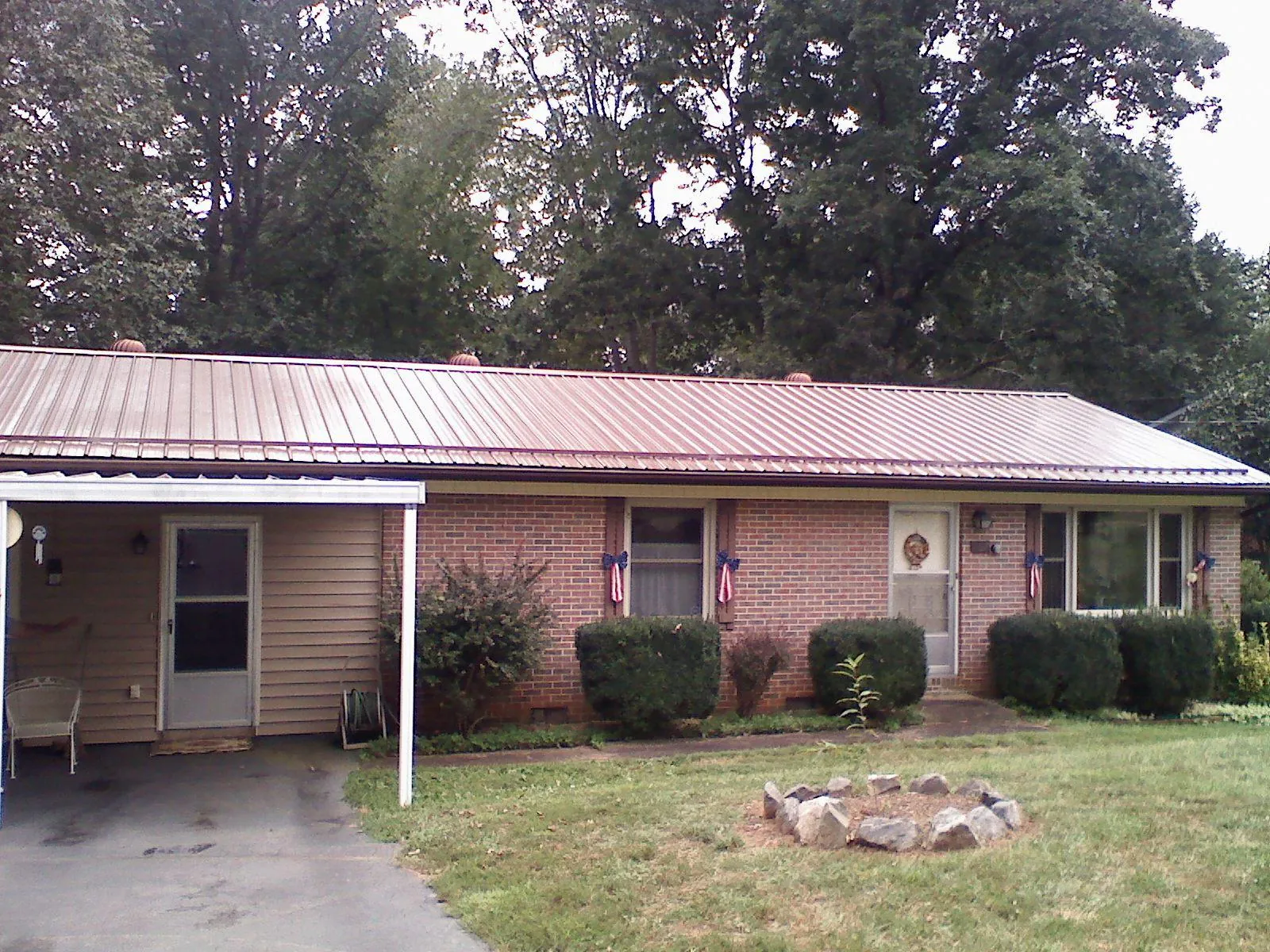 Bronze metal roof and carport on a brick ranch home — Roof Repair work by our crew in Petroleum
