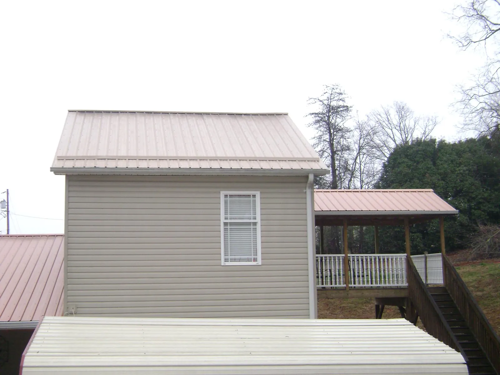 Tan metal roofs on a two story addition and attached porch, from a Roof Replacement job in Petroleum