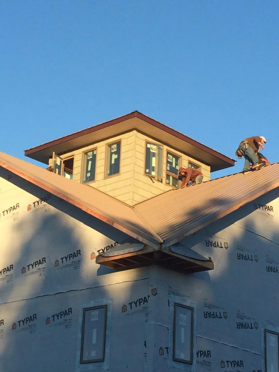 Roofers working around a rooftop cupola on a new metal roof at sunset — Roof Waterproofing in Petroleum by Roofing Brothers